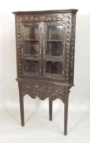 A Victorian ebonised and carved oak standing corner cabinet