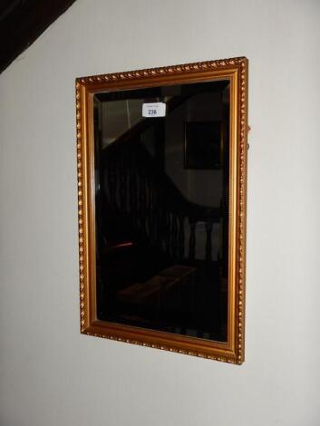 A small gilt framed bevelled rectangular wall mirror.