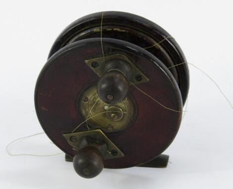 A stained oak and brass fishing reel