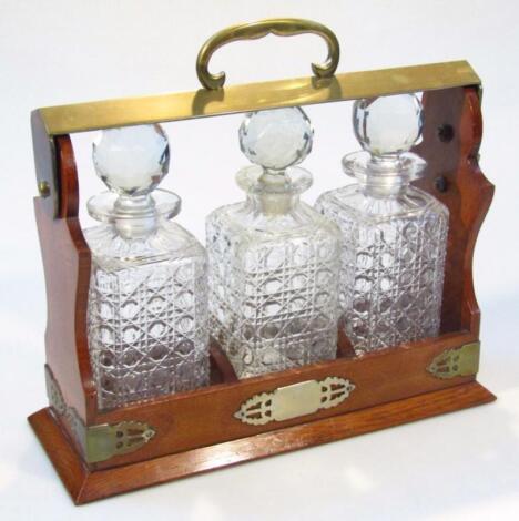 An early 20thC oak and metal cased three bottle tantalus