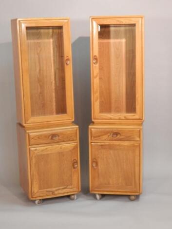A pair of Ercol light elm narrow display cabinets