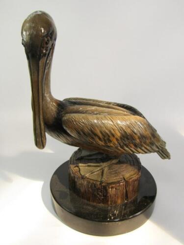 A pottery figure of a pelican perched on a tree trunk