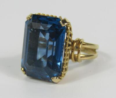 A yellow metal and emerald cut blue topaz dress ring