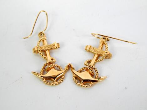 A pair of yellow metal furled anchor earrings on a hook fitting