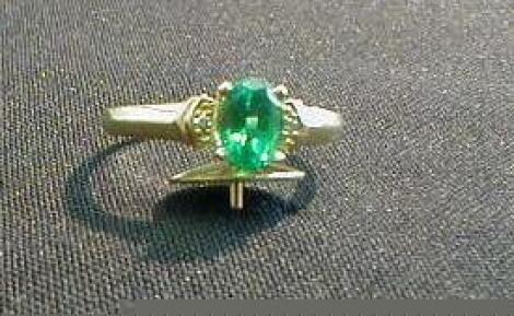 A ladies dress ring set centrally with an oval emerald