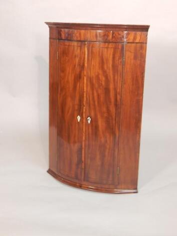 An early 19thC figured mahogany bow fronted corner cabinet