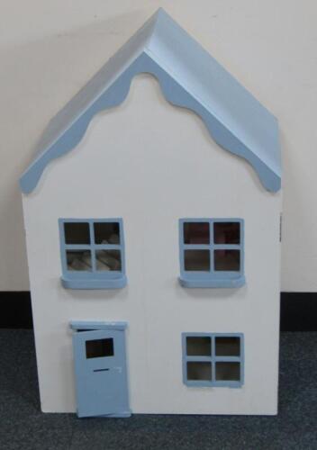 A wooden two storey single door dolls house with a few pieces of furniture