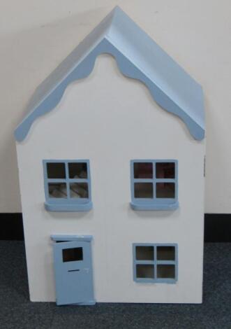 A wooden two storey single door dolls house with a few pieces of furniture