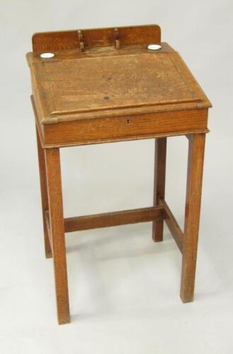 An early 20thC oak school desk with sloping front