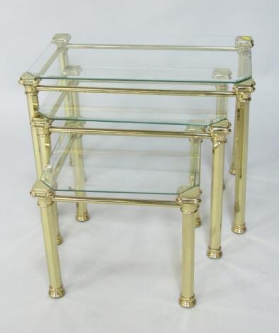 A nest of brass and glass topped coffee tables