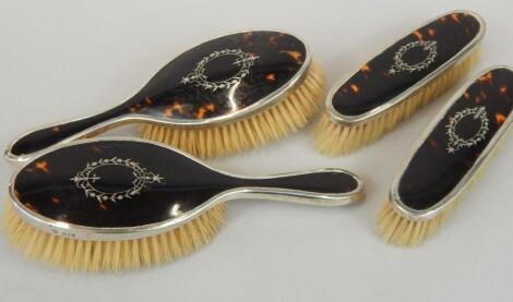 A George V silver and tortoiseshell four piece dressing table set