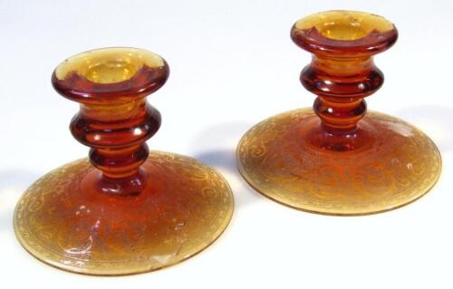 A pair of amber and etched glass squat dwarf candlesticks