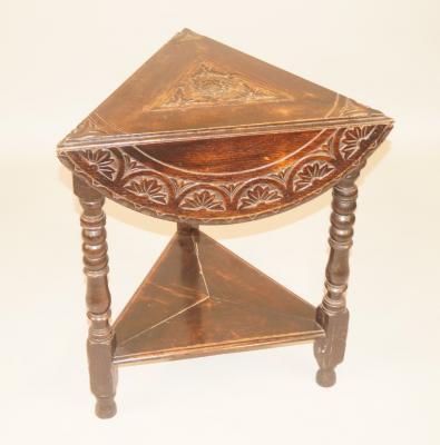 A late Victorian ebonised and carved oak triangular drop leaf table