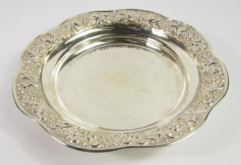 A white metal dish with an embossed foliate rim