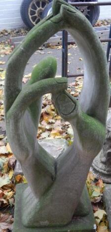 A modernist stone sculpture modelled as joined hands