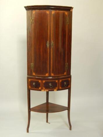 A George III mahogany and satinwood inlaid bow front corner cupboard on stand