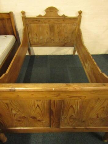 A pine single bed with carved headboard