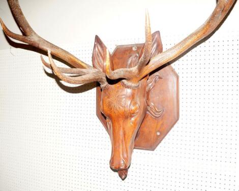 A pair of stag antlers set into a carved wooden head