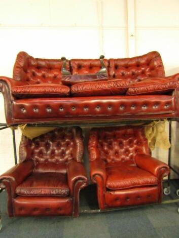 A red leather button back and brass studded three piece suite