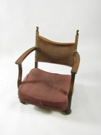 An early 20thC oak child's chair with an embossed leather back