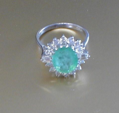 An emerald and diamond oval cluster ring