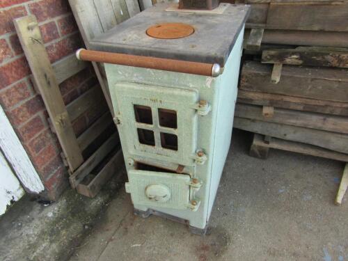 A green enamel cast metal wood burner with back boiler.