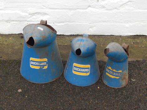 A graduated set of Duckhams blue tin oil dispensers.