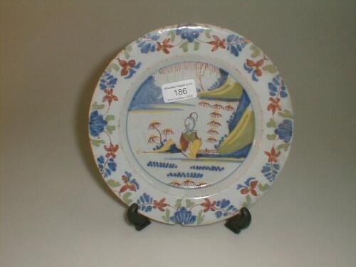 An 18thC Delft plate, painted with a Chinese figure in a landscape, in