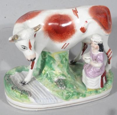 A late 19thC Staffordshire cow and milkmaid figure