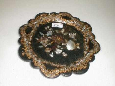 A Victorian papier mache plate of circular form with a scalloped rim