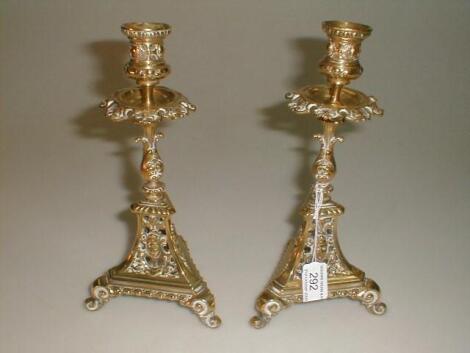 A pair of cast brass candlesticks with shell cast drip trays over water