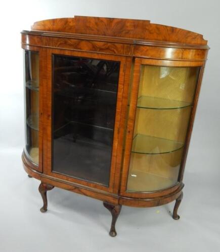 An early 20thC walnut break and bow fronted display cabinet