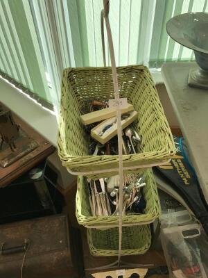 A three tier wicker rack and contents of plated cutlery.