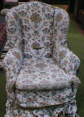 A Georgian style wingback armchair on ball and claw feet with loose needlework