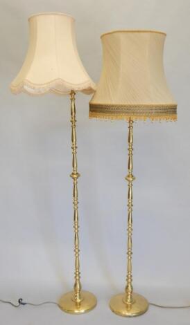 Two similar turned brass standard lamps and shades.