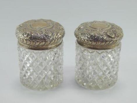 A pair of Victorian cut glass jars with silver lids