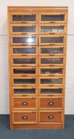 An early 20thC blonde oak haberdasher's cabinet