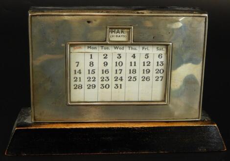An Art Deco silver and mahogany desk calendar