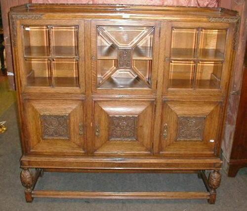 A carved oak display cabinet with bevelled glazed doors and moulded framing