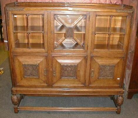 A carved oak display cabinet with bevelled glazed doors and moulded framing