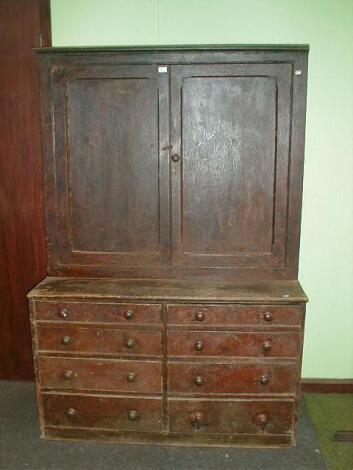 A 19thC pine cabinet with two panelled door top and eight drawer base