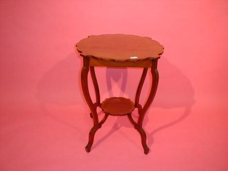 An Edwardian cross banded mahogany window table with shaped top and inter-shelf