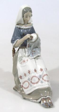 A Lladro figure of a seated lady darning