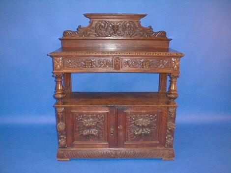 A late Victorian carved oak buffet with lion mask drawer handles and carved
