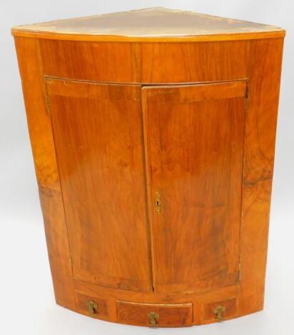 An early 19thC walnut bow fronted corner cabinet