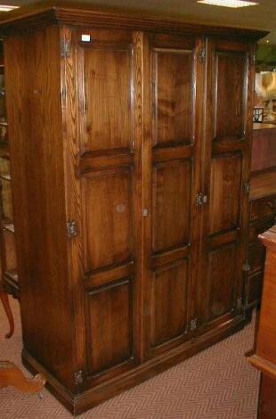 A reproduction triple wardrobe with fielded panel doors