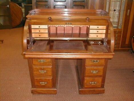 A late Victorian American walnut cylinder top writing desk with a fitted