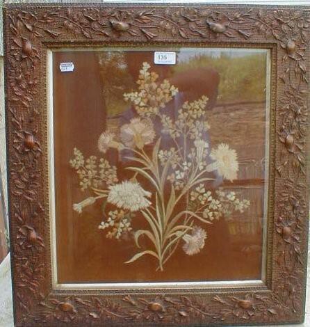 A floral needlework picture enclosed within a moulded high relief floral frame