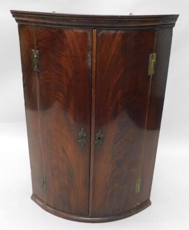 A George III mahogany bow fronted corner cabinet