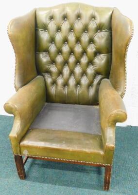 A green leather upholstered wingback chair in George III style